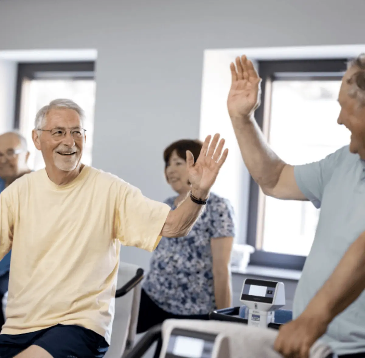 Motivierendes Miteinander bei der Therapie – zwei Männer klatschen sich beim Training sportlich ab und zeigen, wie wirkungsvoll moderne Reha auch im Team funktioniert.