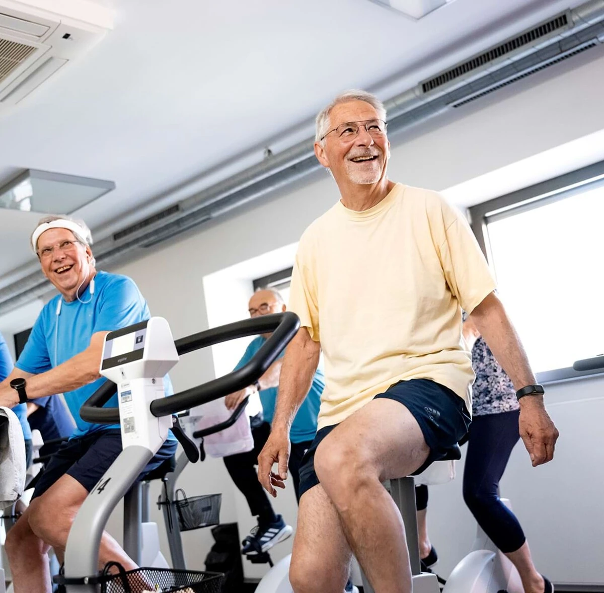 Ein Patient trainiert lächelnd an einem Cardiogerät – Sinnbild für Herz-Kreislauf-Rehabilitation, die neue Lebensqualität schafft.