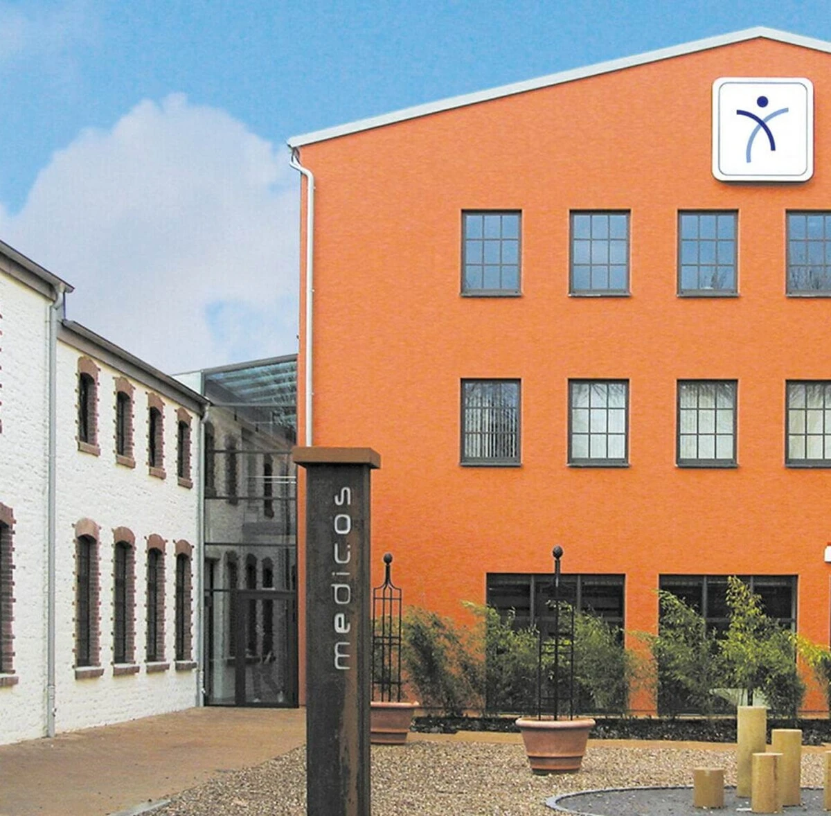 Außenansicht des medicos.Osnabrück: Die umgenutzte Halle mit markanter oranger Fassade verbindet Industriecharme mit moderner Gesundheitsversorgung.