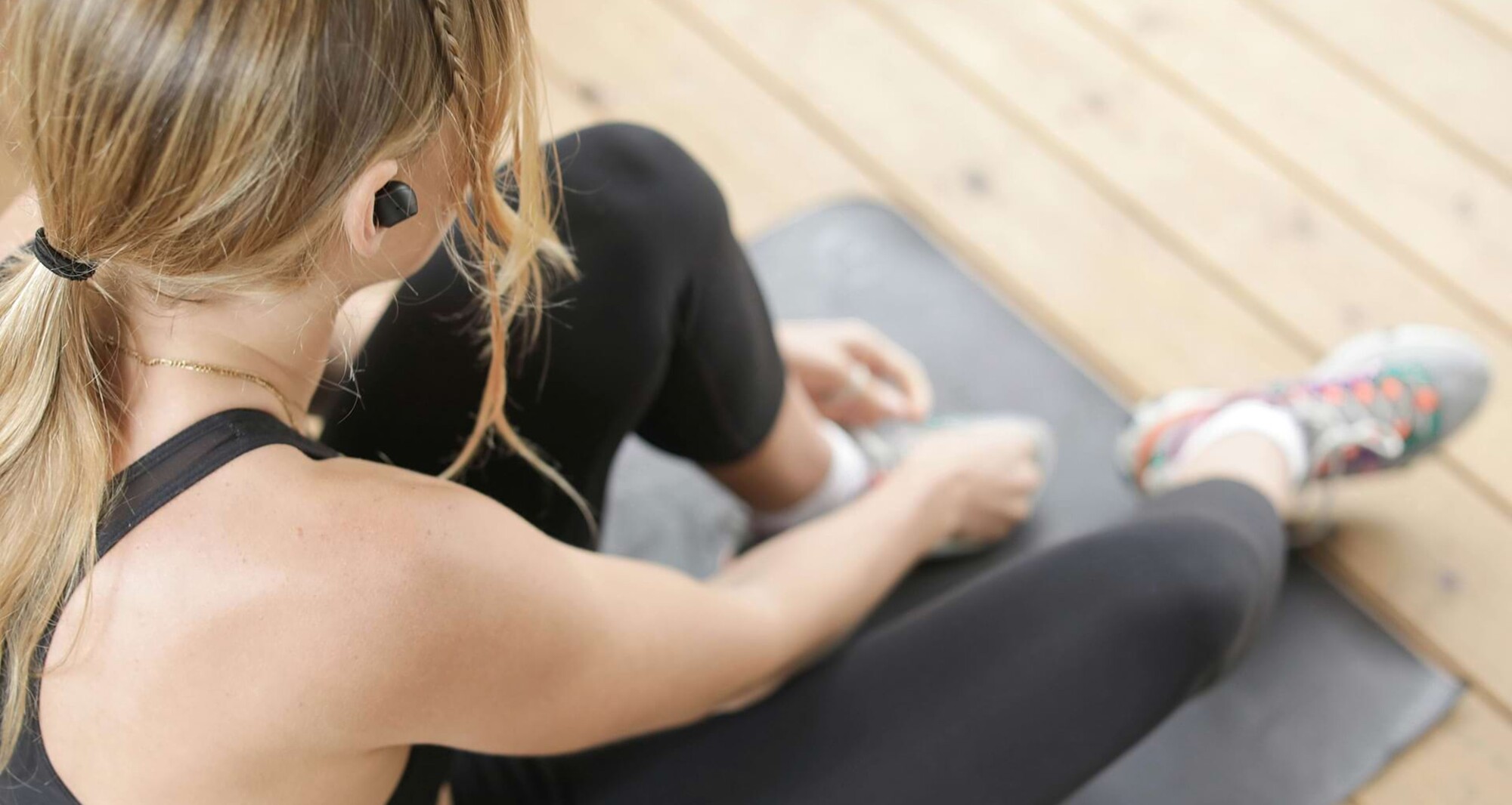 Eine Frau sitzt auf einer Sportmatte und macht Dehnungsübungen