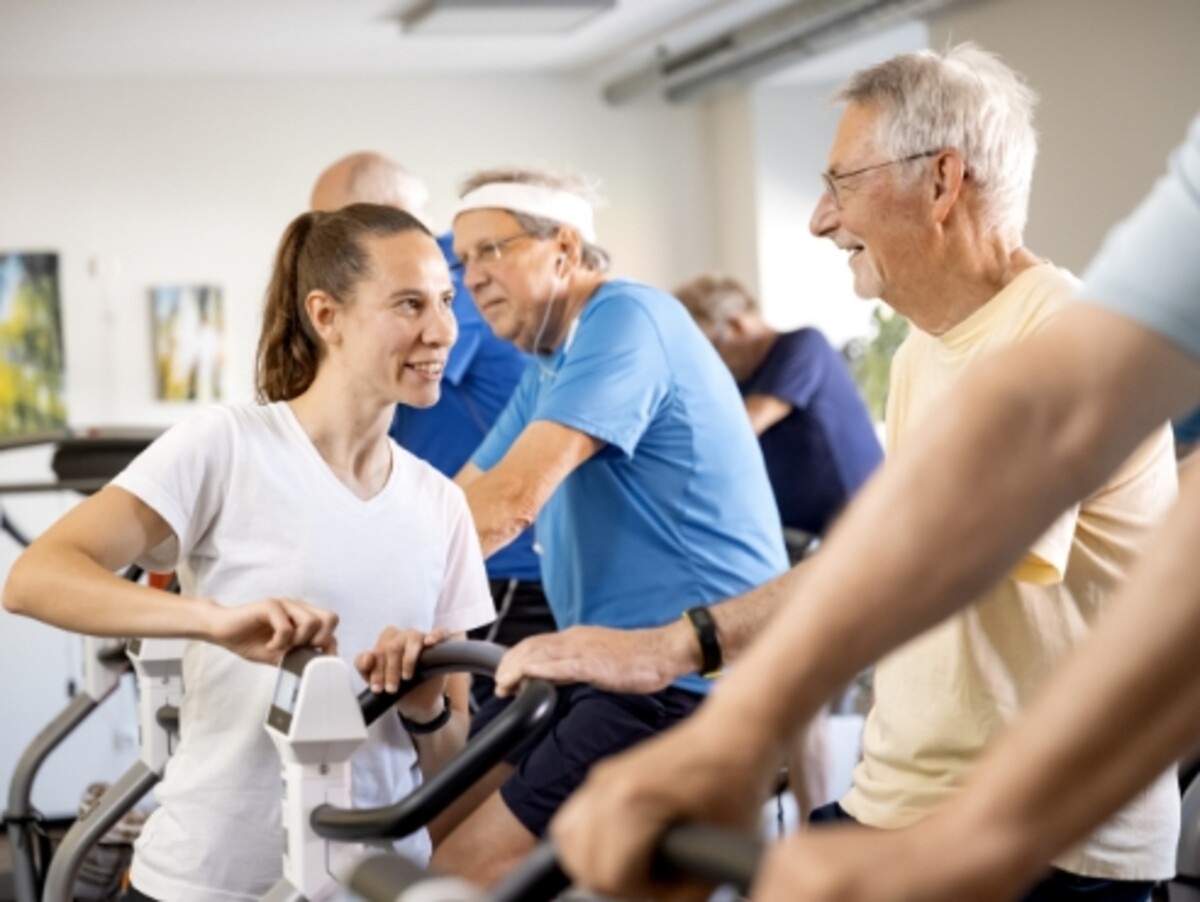 Ältere Herren trainieren auf Fahrradergometern unter Anleitung einer Trainerin – stellvertretend für die orthopädische Reha-Nachsorge und den Rehasport bei medicos.Osnabrück, die helfen, Therapieerfolge nachhaltig zu festigen.