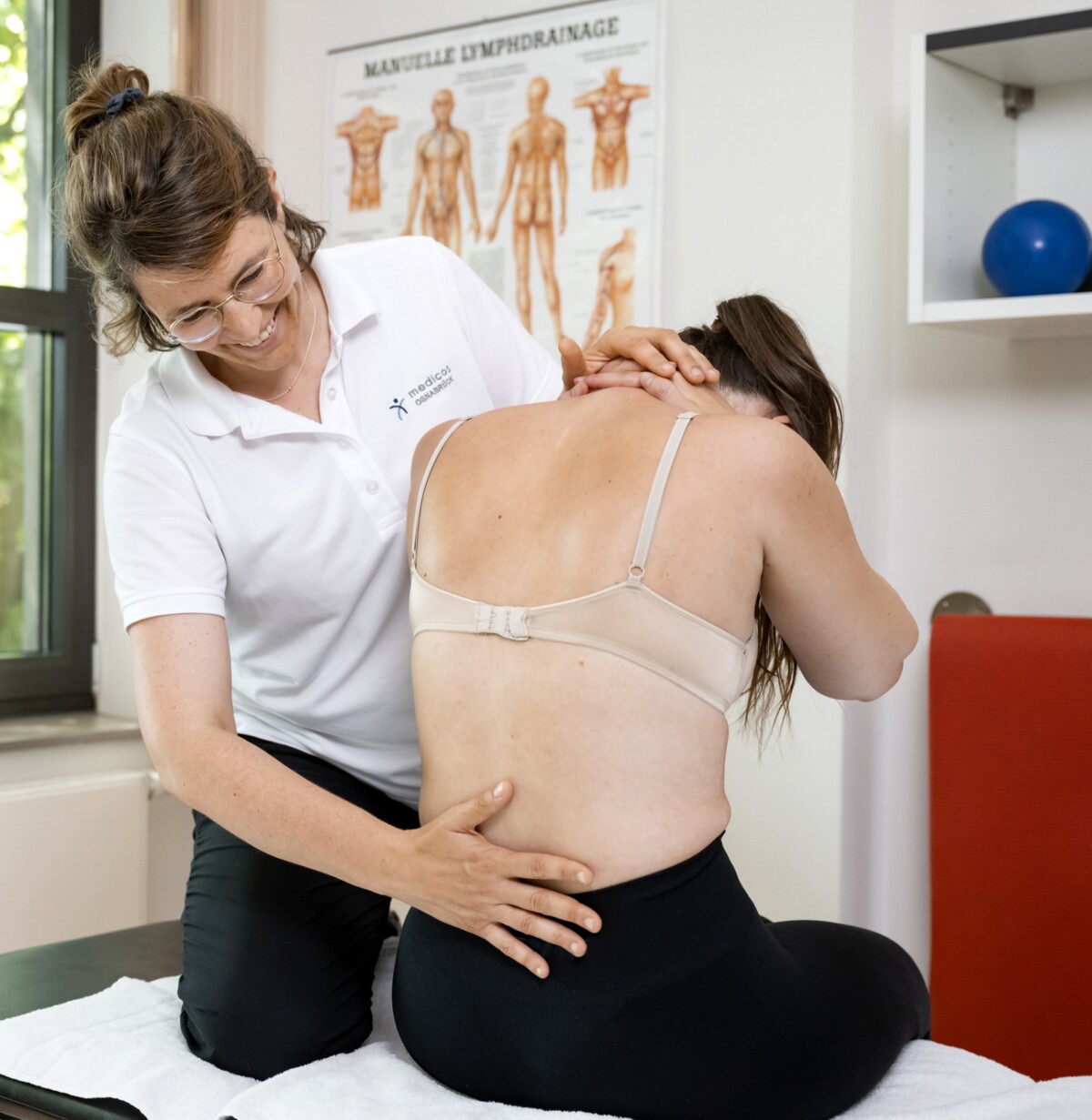 Eine Therapeutin ertastet den Rücken einer Patientin und führt eine gezielte Dehnung am Kopf durch – symbolisch für die individuelle Betreuung nach Verletzungen und operativen Eingriffen in der Orthopädie des medicos.Osnabrück.