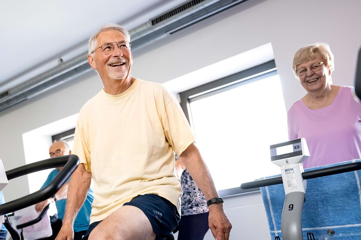 Lachender Mann auf dem Ergometer – steht exemplarisch für die motivierende Atmosphäre und individuelle Begleitung im Reha- und Herzsport zur Stärkung von Ausdauer und Lebensqualität.